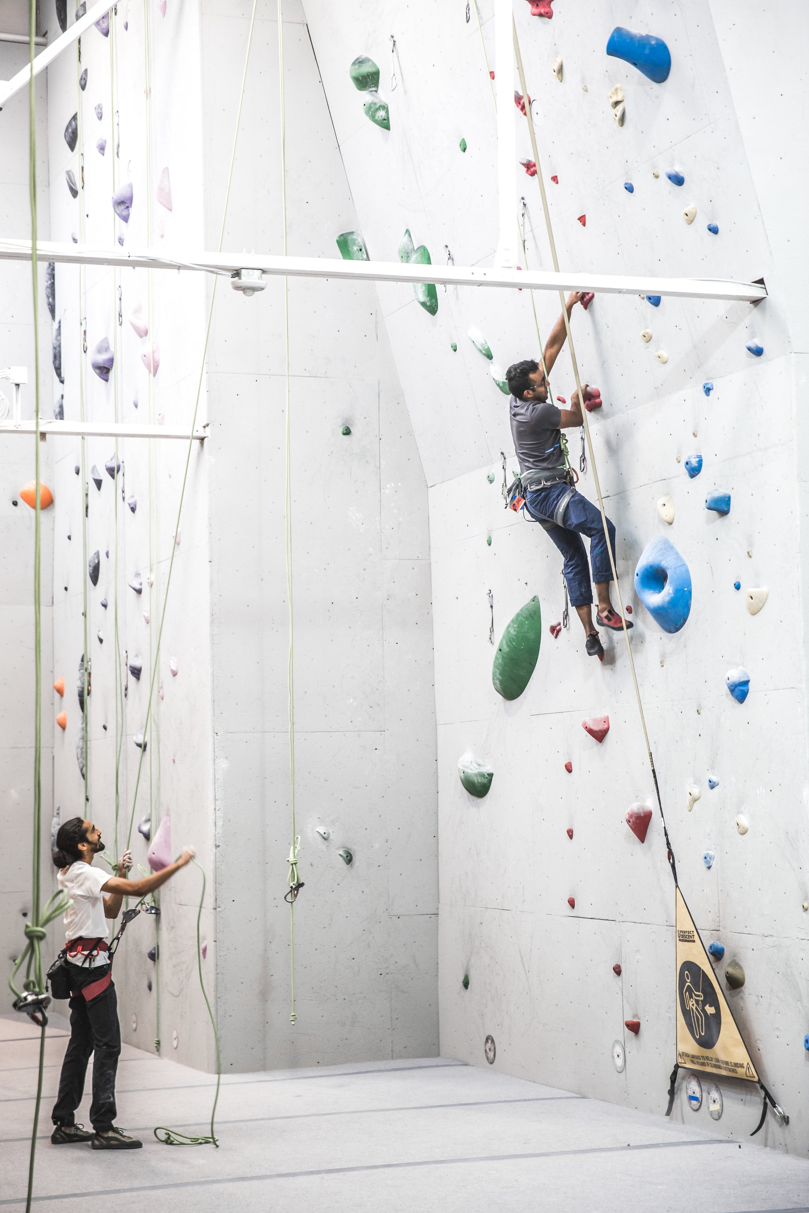 man climbing with a friend at an indoor course